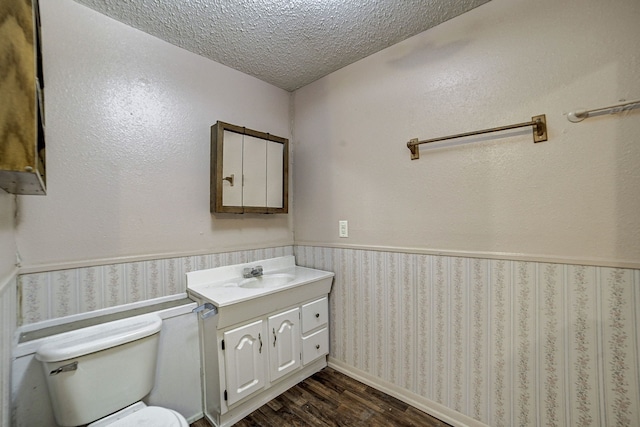 bathroom with toilet, vanity, a textured ceiling, and hardwood / wood-style flooring