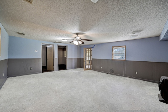 unfurnished room with a textured ceiling, ceiling fan, and wooden walls