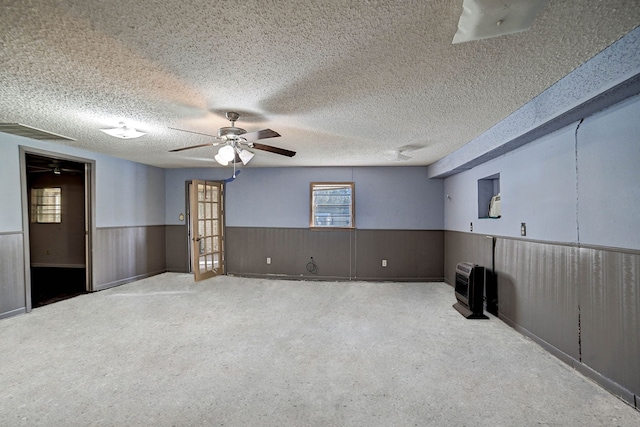 carpeted spare room with a textured ceiling, wooden walls, and heating unit