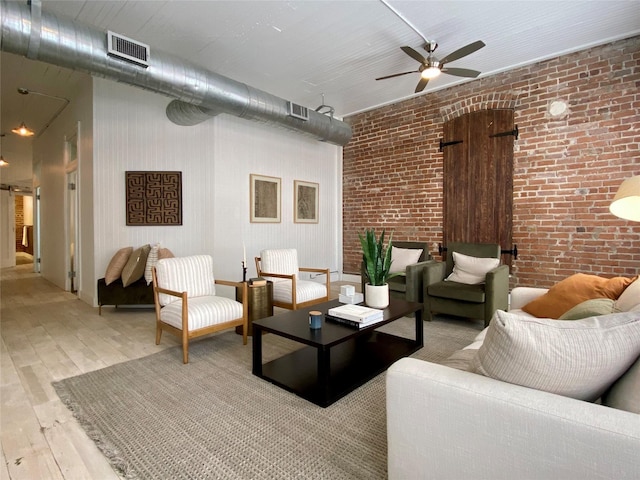 interior space with brick wall, ceiling fan, and light hardwood / wood-style floors