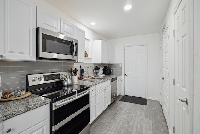 kitchen featuring sink, white cabinets, light stone counters, light wood-type flooring, and appliances with stainless steel finishes