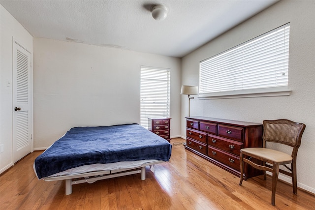 bedroom with a textured ceiling and light wood-type flooring