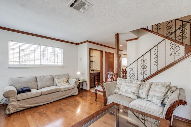 living room with a textured ceiling, crown molding, and hardwood / wood-style flooring