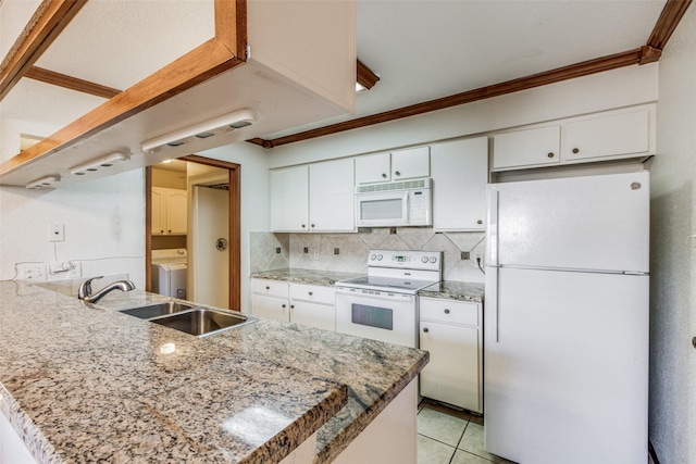 kitchen featuring white appliances, washer / clothes dryer, kitchen peninsula, sink, and white cabinetry