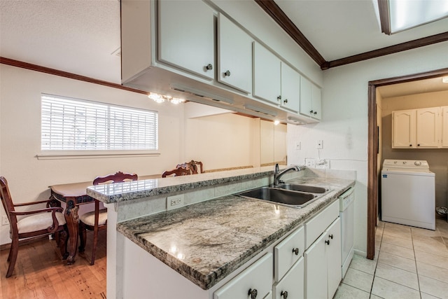 kitchen featuring washer / clothes dryer, kitchen peninsula, white dishwasher, sink, and white cabinetry