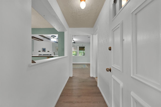 hallway featuring a textured ceiling, beamed ceiling, and hardwood / wood-style floors