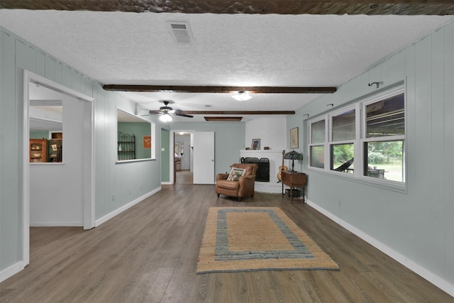 unfurnished room with a textured ceiling, dark wood-type flooring, and beam ceiling