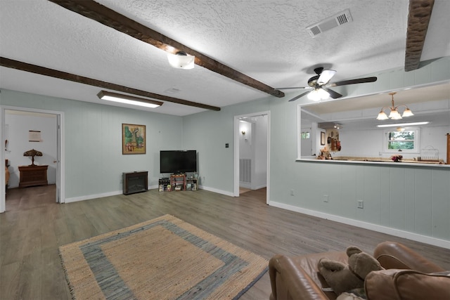 living room featuring beam ceiling, dark wood-type flooring, ceiling fan with notable chandelier, and a textured ceiling