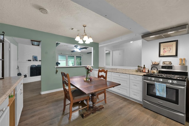 kitchen featuring gas range, a textured ceiling, decorative light fixtures, white cabinetry, and a fireplace