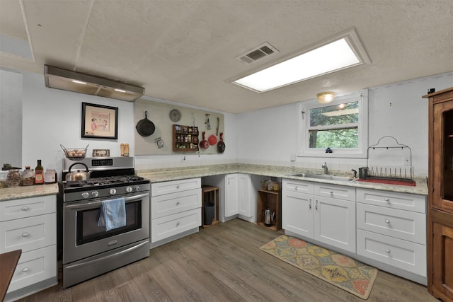 kitchen featuring light stone countertops, stainless steel gas range oven, hardwood / wood-style flooring, sink, and white cabinetry