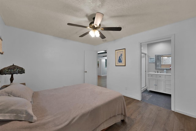 bedroom featuring a textured ceiling, ceiling fan, dark hardwood / wood-style flooring, and connected bathroom