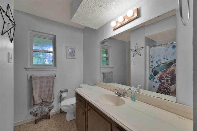 bathroom with toilet, vanity, a textured ceiling, and a wealth of natural light