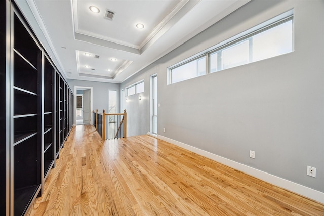 interior space with ornamental molding, hardwood / wood-style floors, and a raised ceiling