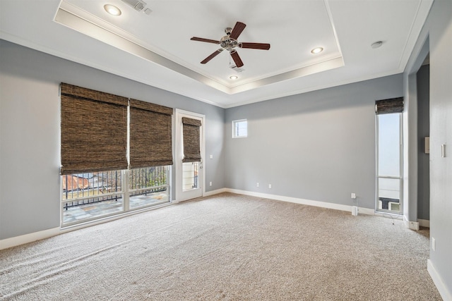 carpeted empty room with a raised ceiling, ceiling fan, and crown molding