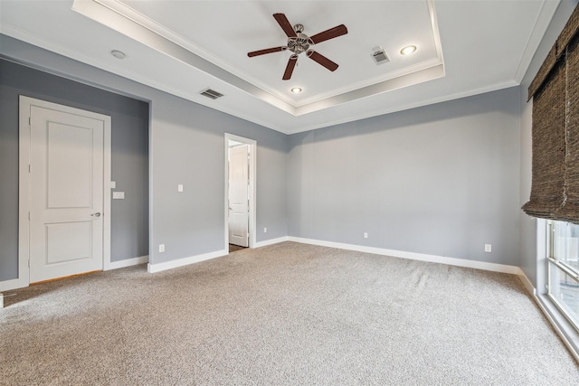 interior space with a raised ceiling, ceiling fan, crown molding, and carpet