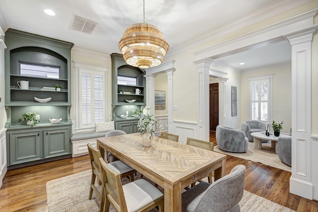 dining area featuring an inviting chandelier, ornamental molding, plenty of natural light, and light hardwood / wood-style floors