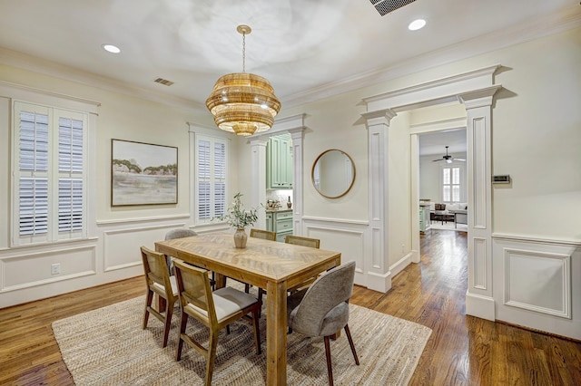 dining room with hardwood / wood-style flooring, ornamental molding, ceiling fan with notable chandelier, and decorative columns