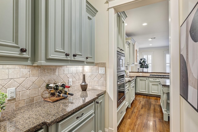 kitchen featuring dark wood-type flooring, crown molding, tasteful backsplash, stone countertops, and stainless steel appliances