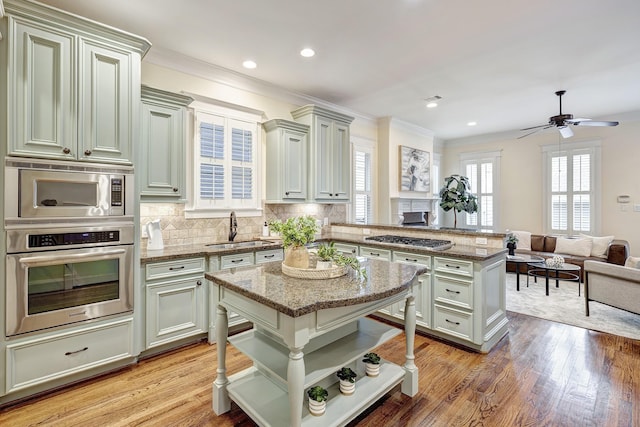 kitchen featuring appliances with stainless steel finishes, light stone countertops, sink, and a kitchen island