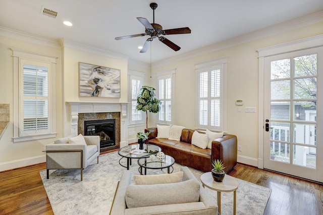 living room featuring hardwood / wood-style floors, a fireplace, ornamental molding, and ceiling fan