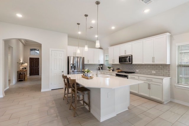 kitchen with white cabinets, sink, appliances with stainless steel finishes, and an island with sink