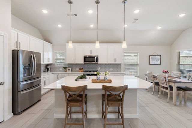 kitchen featuring white cabinets, pendant lighting, stainless steel appliances, and a kitchen island