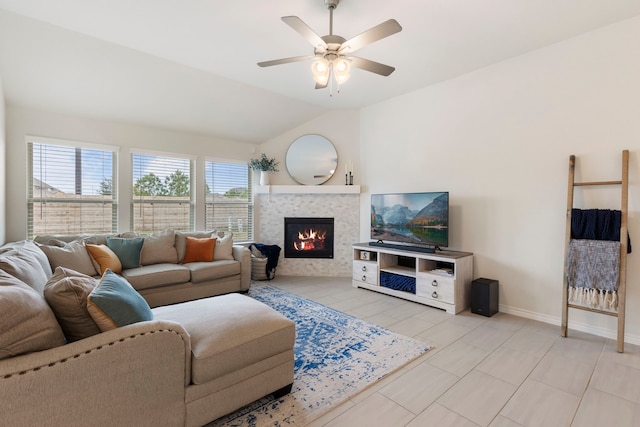 living room with ceiling fan, vaulted ceiling, and a tiled fireplace