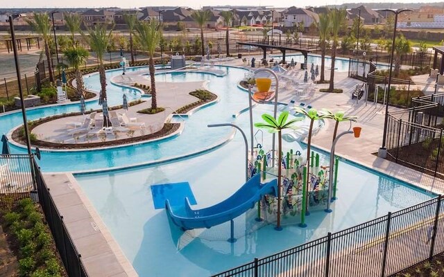 view of swimming pool featuring a water play area, a water slide, a residential view, and fence