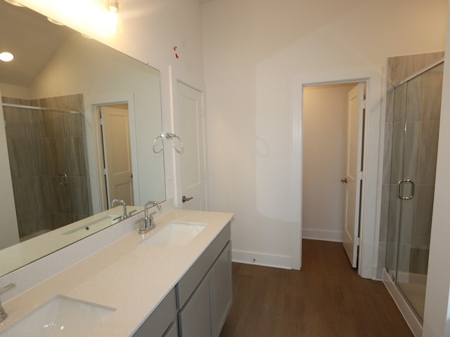597 Copper Springs Dr, Magnolia, TX 77354 - bathroom featuring double vanity, a stall shower, wood finished floors, vaulted ceiling, and baseboards
