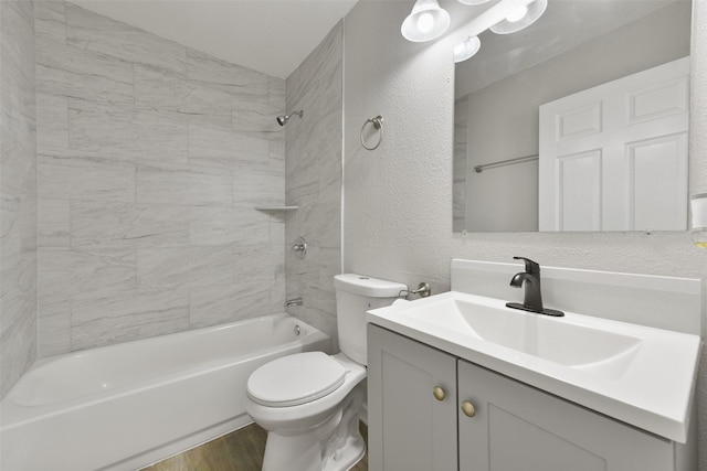 full bathroom with tiled shower / bath, hardwood / wood-style floors, vanity, and toilet