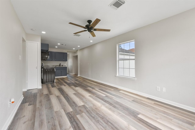 unfurnished living room with ceiling fan, wood-type flooring, and sink