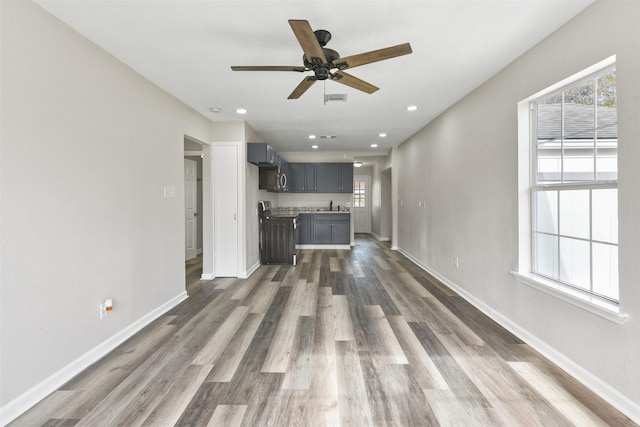 unfurnished living room featuring ceiling fan, dark hardwood / wood-style flooring, and sink