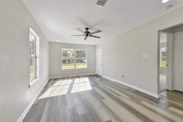 empty room with ceiling fan, light hardwood / wood-style flooring, and plenty of natural light