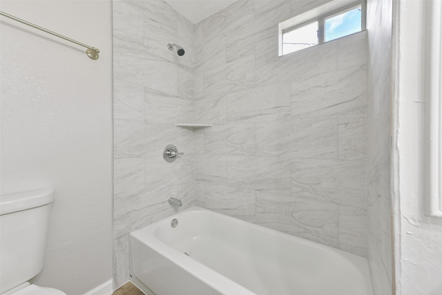 bathroom featuring toilet and tiled shower / bath