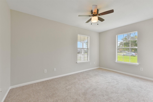 carpeted spare room with ceiling fan and plenty of natural light