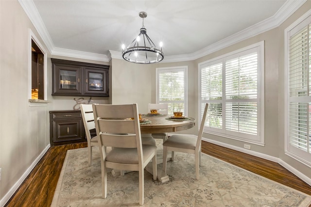 dining area with dark wood-type flooring, ornamental molding, and a chandelier