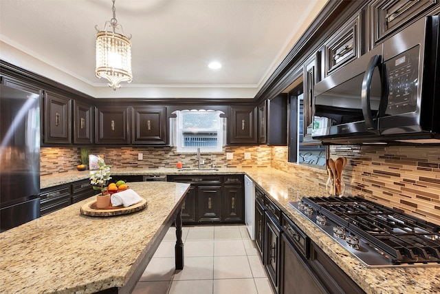 kitchen with stainless steel appliances, sink, an inviting chandelier, hanging light fixtures, and dark brown cabinetry