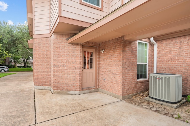 view of exterior entry with a patio and central AC