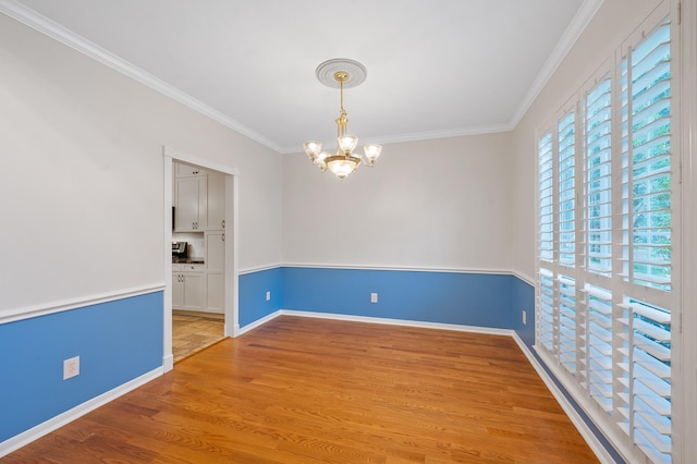 spare room with a chandelier, crown molding, and light hardwood / wood-style flooring