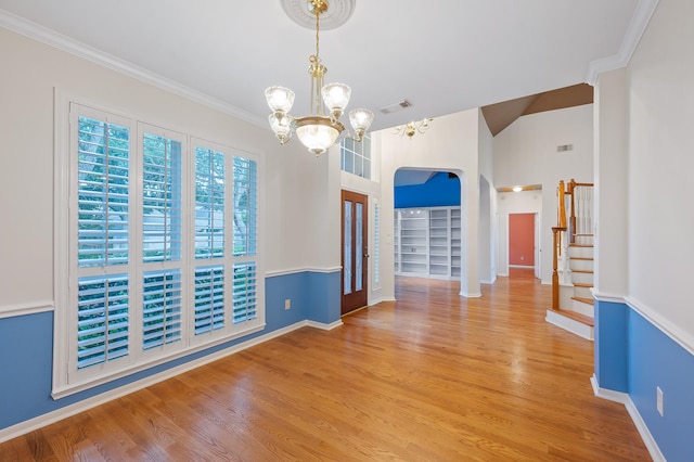 unfurnished room with ornamental molding, light wood-type flooring, a notable chandelier, and built in features