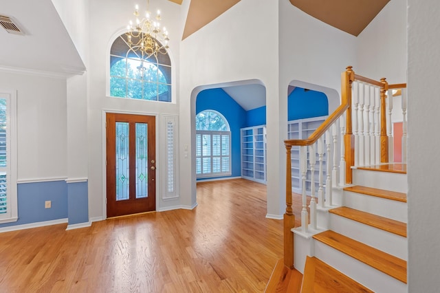 foyer with light hardwood / wood-style flooring, high vaulted ceiling, and a chandelier