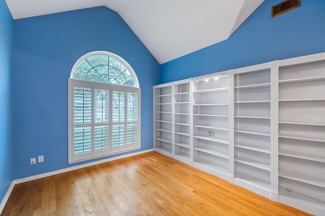 empty room with vaulted ceiling and hardwood / wood-style floors