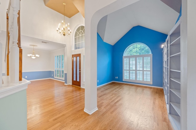 unfurnished living room with decorative columns, vaulted ceiling, a chandelier, and hardwood / wood-style floors