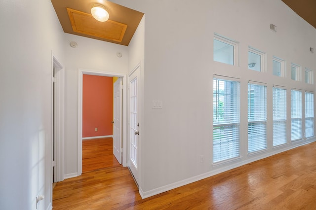 hall featuring light hardwood / wood-style floors and a towering ceiling