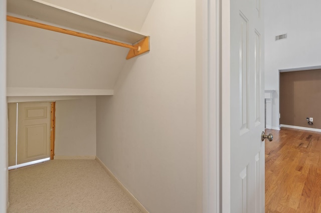 hall featuring vaulted ceiling and light colored carpet