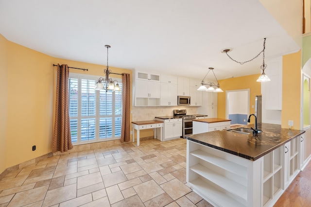 kitchen featuring kitchen peninsula, pendant lighting, white cabinetry, appliances with stainless steel finishes, and sink