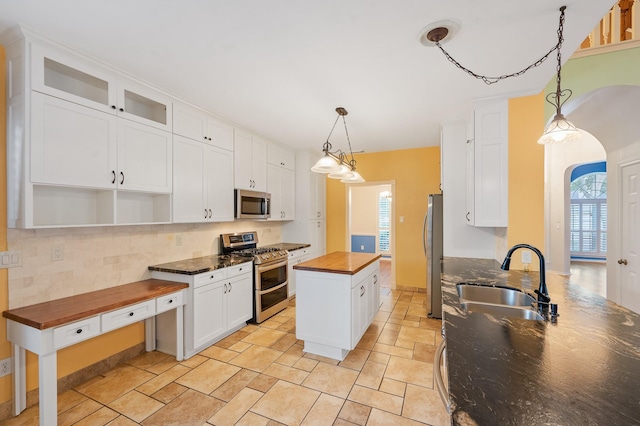 kitchen featuring stainless steel appliances, sink, white cabinets, butcher block countertops, and a kitchen island