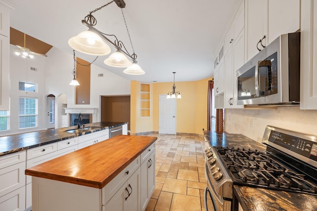 kitchen featuring a kitchen island, stainless steel appliances, white cabinets, and wooden counters