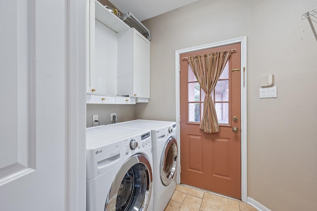 laundry area featuring washing machine and dryer, light tile patterned floors, and cabinets