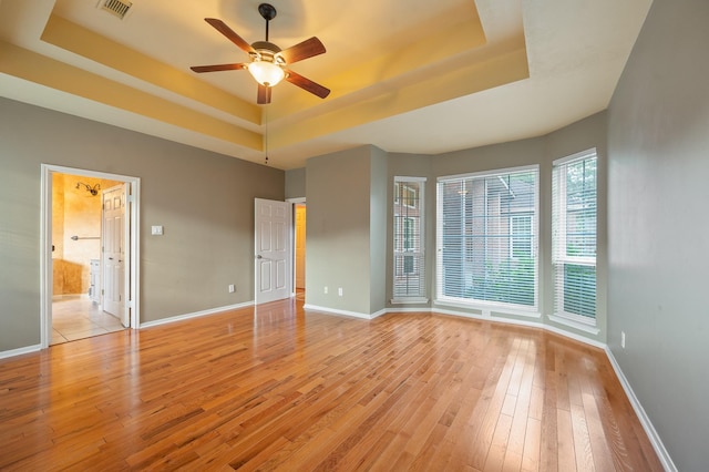 spare room with a raised ceiling, ceiling fan, and light hardwood / wood-style floors